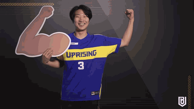 a man in a blue and yellow uprising jersey holds up his fist