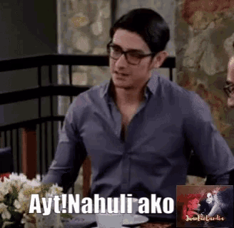 a man wearing glasses is sitting at a table with ayt nahuli ako written on it