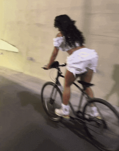 a woman in white shorts is riding a bike on a street