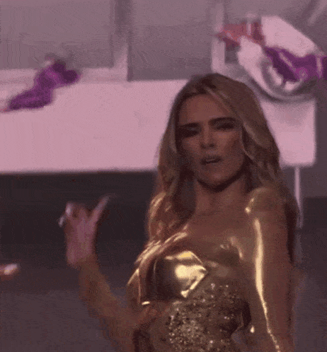 a woman in a gold dress is standing on a stage