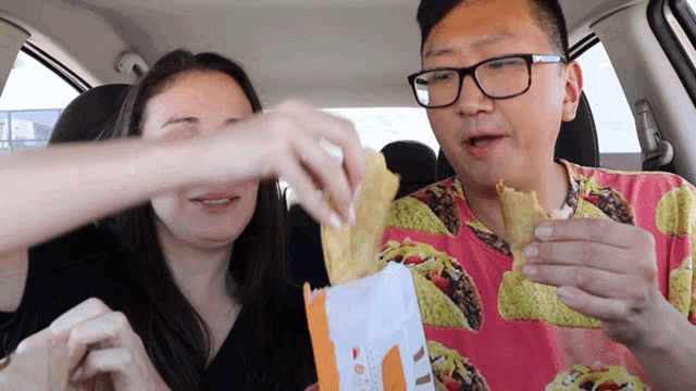 a man in a taco shirt is eating a tortilla chip from a bag