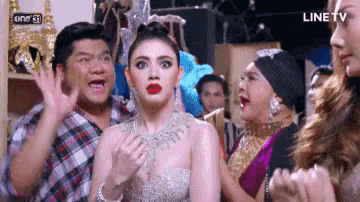 a group of people are standing around a woman who is wearing a dress .