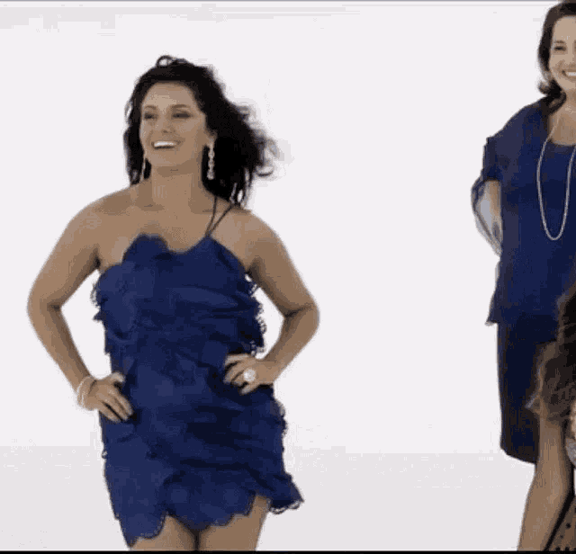 a woman in a blue dress is smiling and dancing