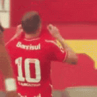 a man in a red jersey with the number 10 on it is flexing his arms .
