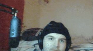 a man wearing headphones and a beanie is standing in front of a microphone