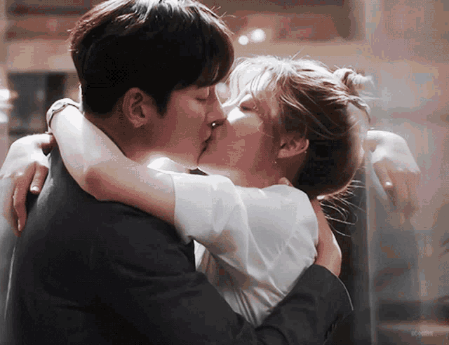a man and a woman are kissing in front of a sign that says ' x ' on it