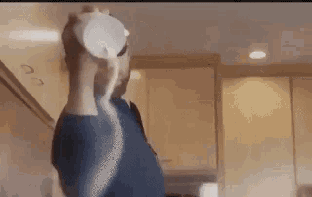 a man is pouring milk from a cup into a glass in a kitchen .