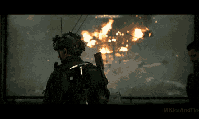 a man in a helmet stands in front of a window with a fire in the background