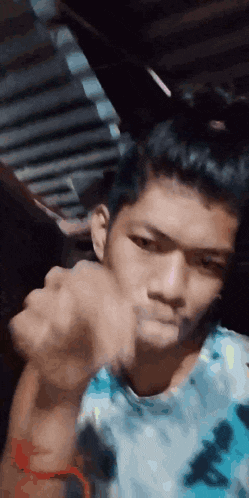 a young man in a blue shirt is making a funny face with his fist