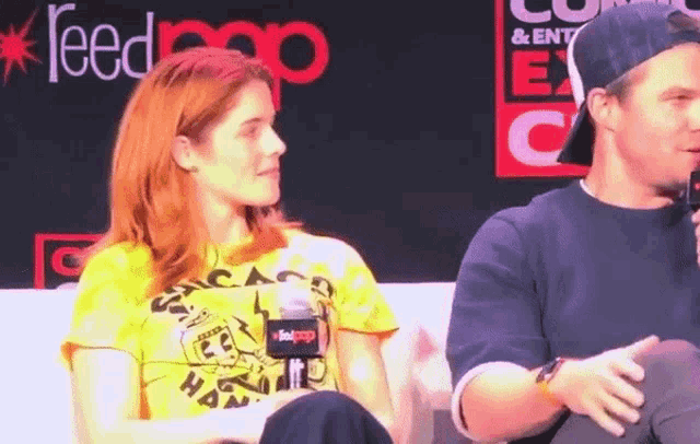 a woman wearing a yellow shirt that says chicago on it sits next to a man