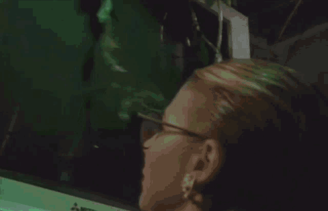 a woman wearing glasses looks at a screen that says " i life "