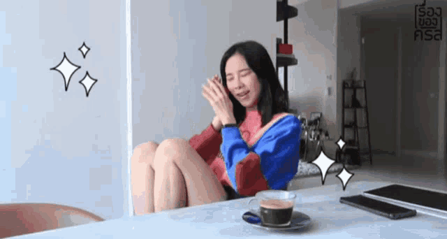 a woman sits at a table with a cup of coffee in front of her and a sign that says say no