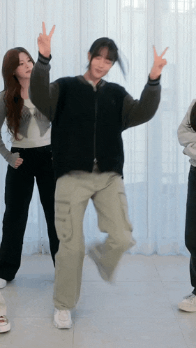 a woman in a black jacket and khaki pants is dancing