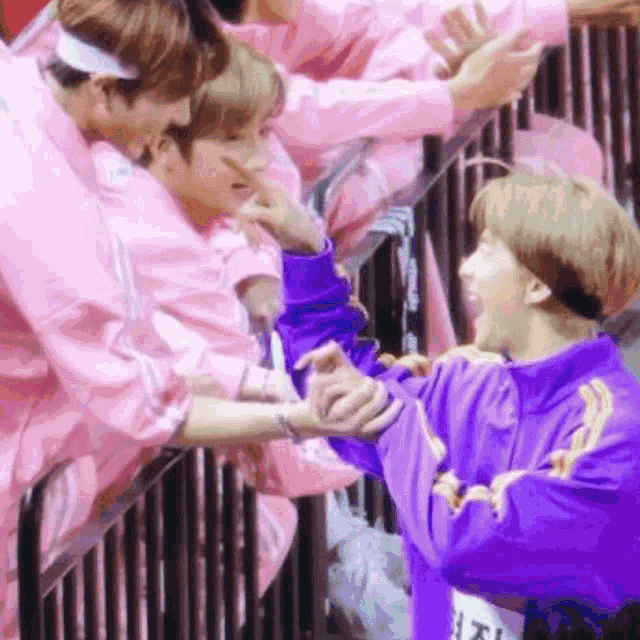 a group of people wearing pink jackets and purple jackets are standing next to each other .