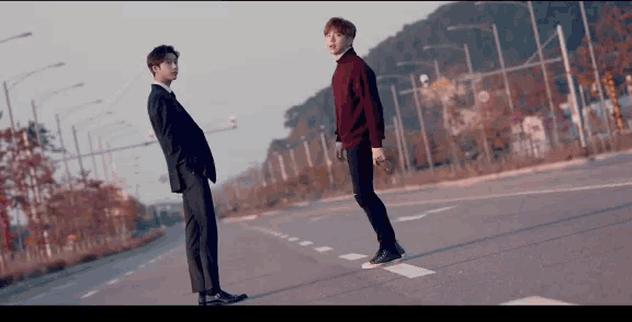 two men are standing on the side of a road .