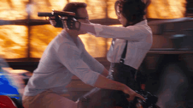 a woman is holding a gun to a man 's face in a blurry photo