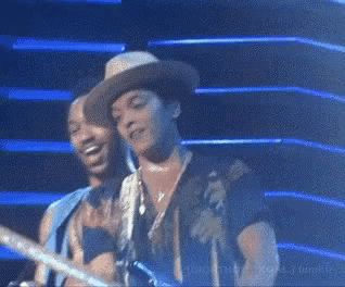 a man in a hat is singing into a microphone on a stage