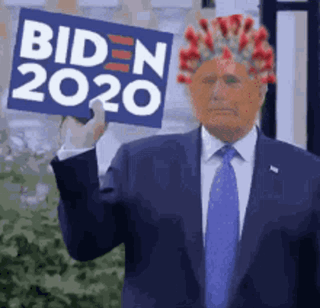 a man in a suit and tie is holding a sign that says biden 2020 on it .