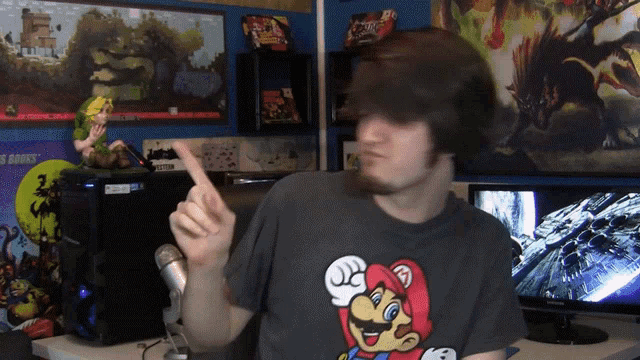 a man wearing a mario t-shirt is pointing up