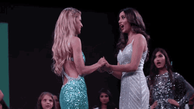 two women are standing next to each other and shaking hands