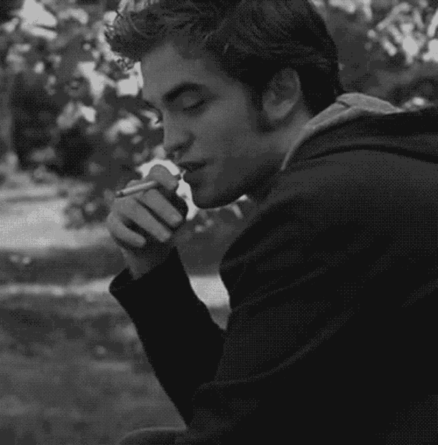 a black and white photo of a man smoking a cigarette .
