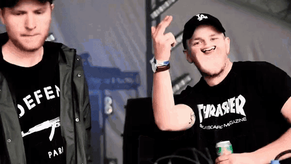 a man wearing a thrasher t-shirt holds a can of soda