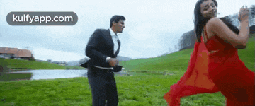 a man and a woman are dancing in a grassy field .