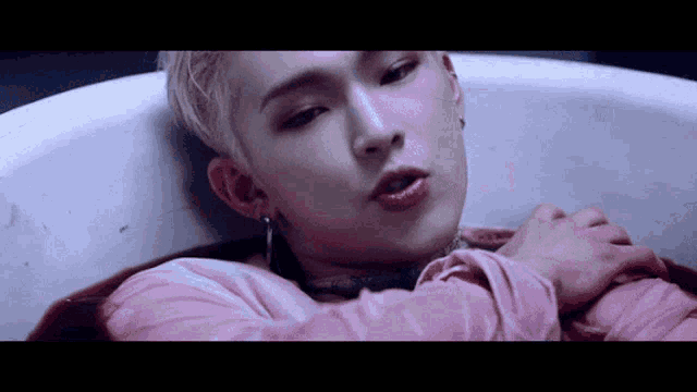 a man in a pink shirt is laying in a bathtub