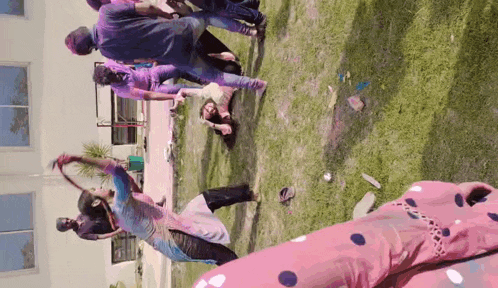 a group of people are playing with colored powder on the grass