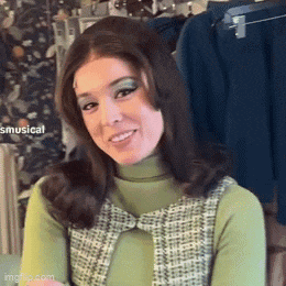 a woman in a green and white dress is smiling and looking at the camera .