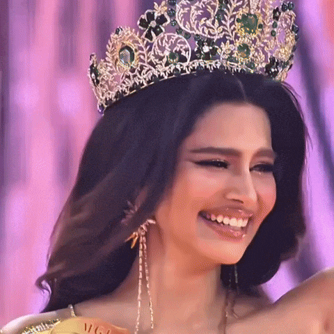 a woman wearing a crown and earrings smiles