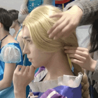 a woman in a purple dress has her hair braided