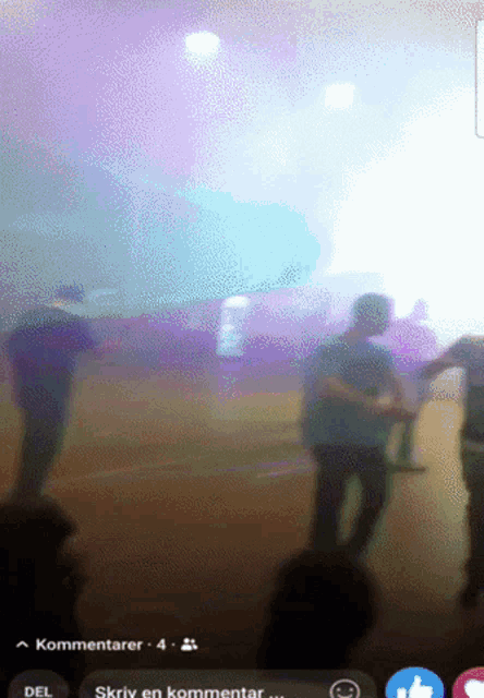 a blurred image of a group of people standing in front of a stage with a purple light behind them