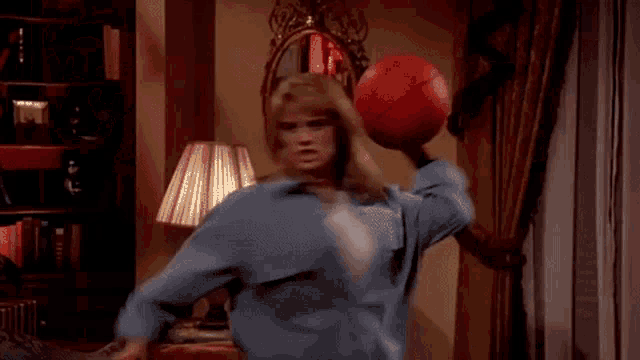 a woman is holding a red basketball over her head in a living room .