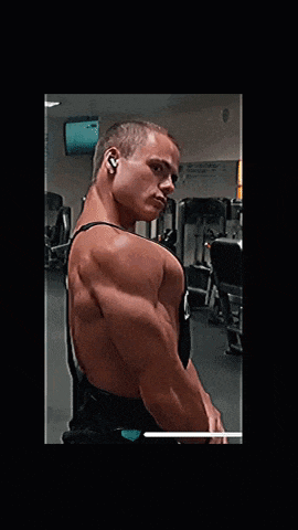a man in a gym with a black tank top that says b on it