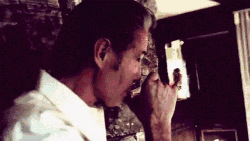 a man with blood on his face is standing in front of a fireplace .