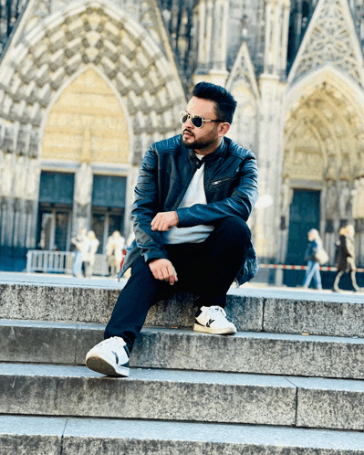 a man wearing sunglasses sits on a set of stairs