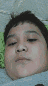 a close up of a person 's face with a green blanket behind him