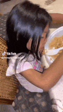 a little girl is sitting at a table eating cereal from a bowl .