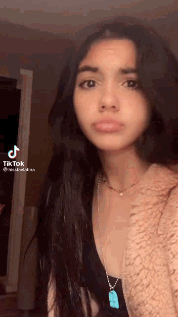 a tiktok video of a girl with long hair and a necklace