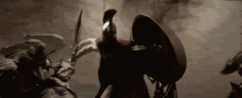 a man in a spartan helmet is holding a sword and shield in a battle scene .