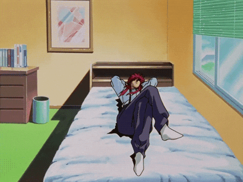 a man with red hair sits on a bed in a bedroom