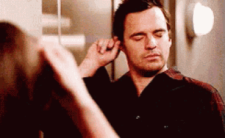 a man is looking at himself in a mirror while a woman adjusts his ear .