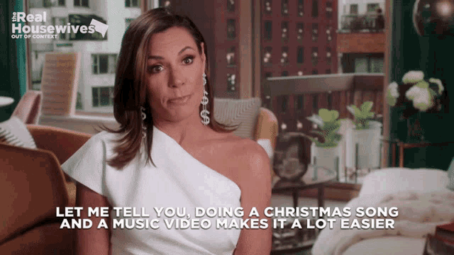 a woman in a white one shoulder dress says " let me tell you doing a christmas song "
