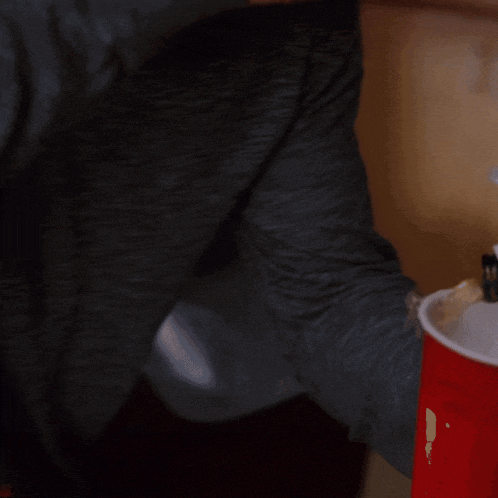a man in a black jacket is holding a red cup