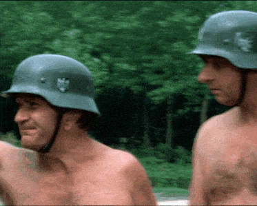 two shirtless men wearing helmets with a lion on the front