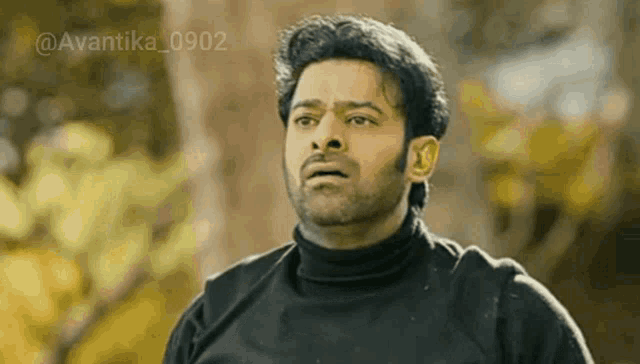 a man with a beard is wearing a black turtleneck sweater and making a funny face .