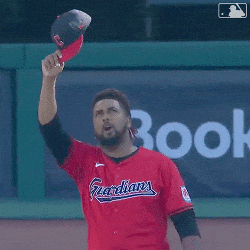a man in a red jersey with the word indians on it throws a baseball