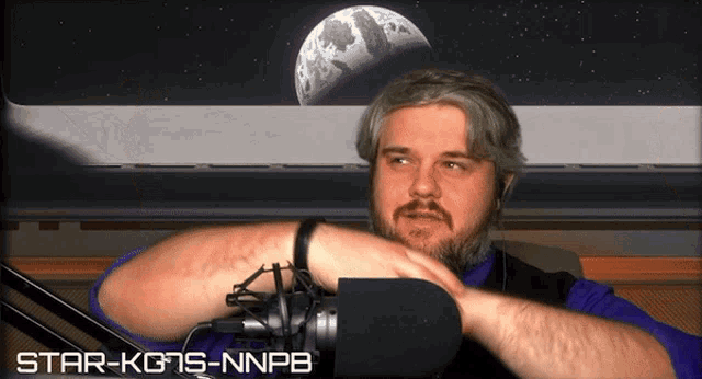 a man sitting in front of a microphone with the words star-kgs-nnpb below him