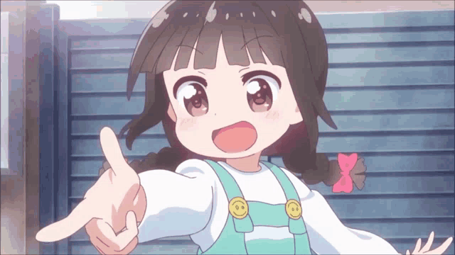 a little girl with pigtails and overalls is pointing at something